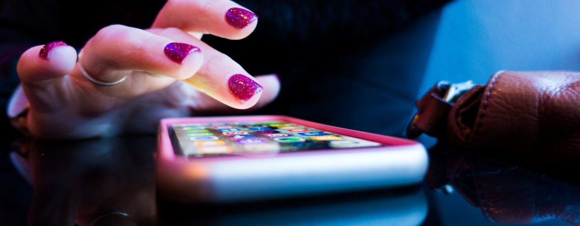 person using black smartphone with gray and pink case